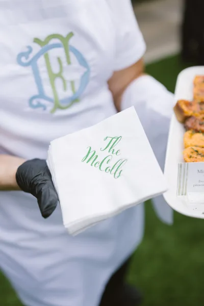 Wedding cocktail napkins with personalized wedding napkins green calligraphy monogram served on an appetizer tray by a gloved server outdoors
