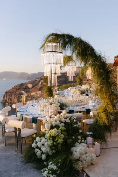 Reception tablescape showcasing outdoor reception decor with chandeliers, overlooking the ocean and cliffs beneath a wide sky.