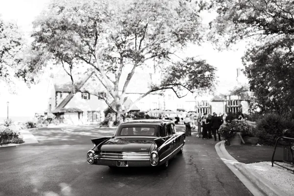Wedding getaway car, a vintage wedding car parked on a tree-lined estate driveway as wedding guests gather for the send-off