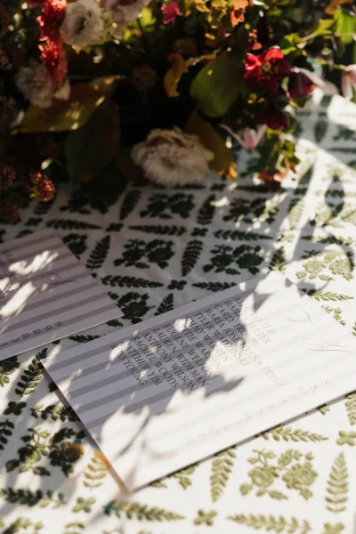 Escort cards and wedding escort cards in striped black and white with calligraphy beside a floral centerpiece on a sunlit tablecloth