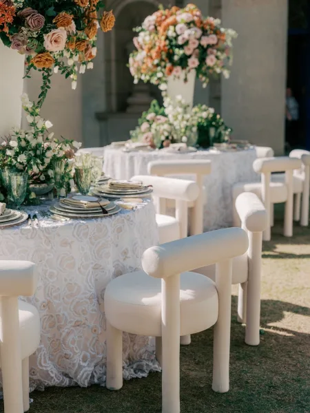 Reception tablescape showcasing outdoor reception decor with tall centerpieces, set beneath a stone archway in a courtyard lawn.